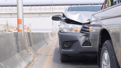 A rear-end Uber accident next to a concrete barrier on a highway.
