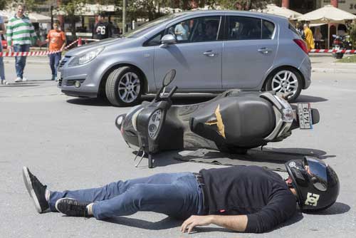 A man lying in the street after being in a motorcycle accident. 