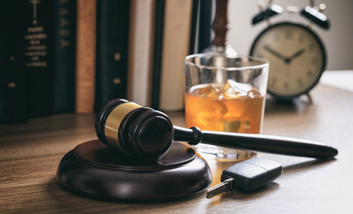 A gavel sitting next to a glass of alcohol. 