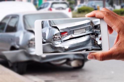A person taking photos of damaged caused by a rear-end car accident.